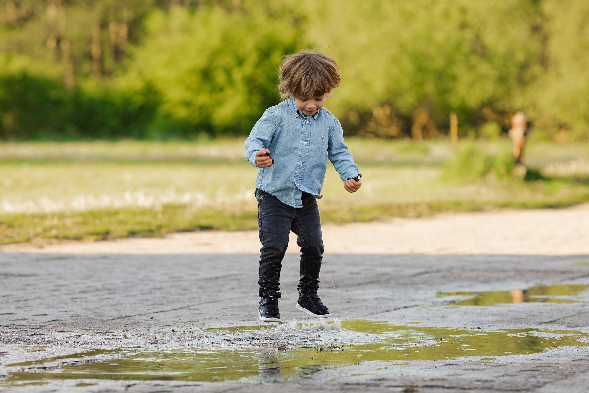 Enfant portant une chemise et un jean au bord d'une flaque d'eau