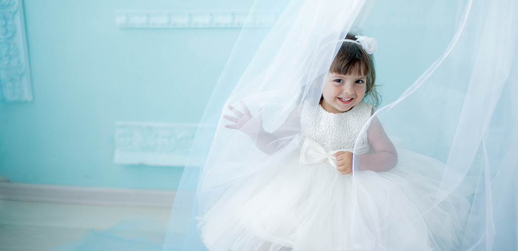 Petite fille habillée tout en blanc pour une cérémonie. Jolie robe tutu et serre-tête à fleur blanche. Tenue de cérémonie
